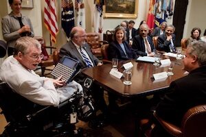 Man with assistive technology device at table with President Obama