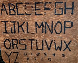 wood plank arved with capital letters A-Z and numbers 0-9