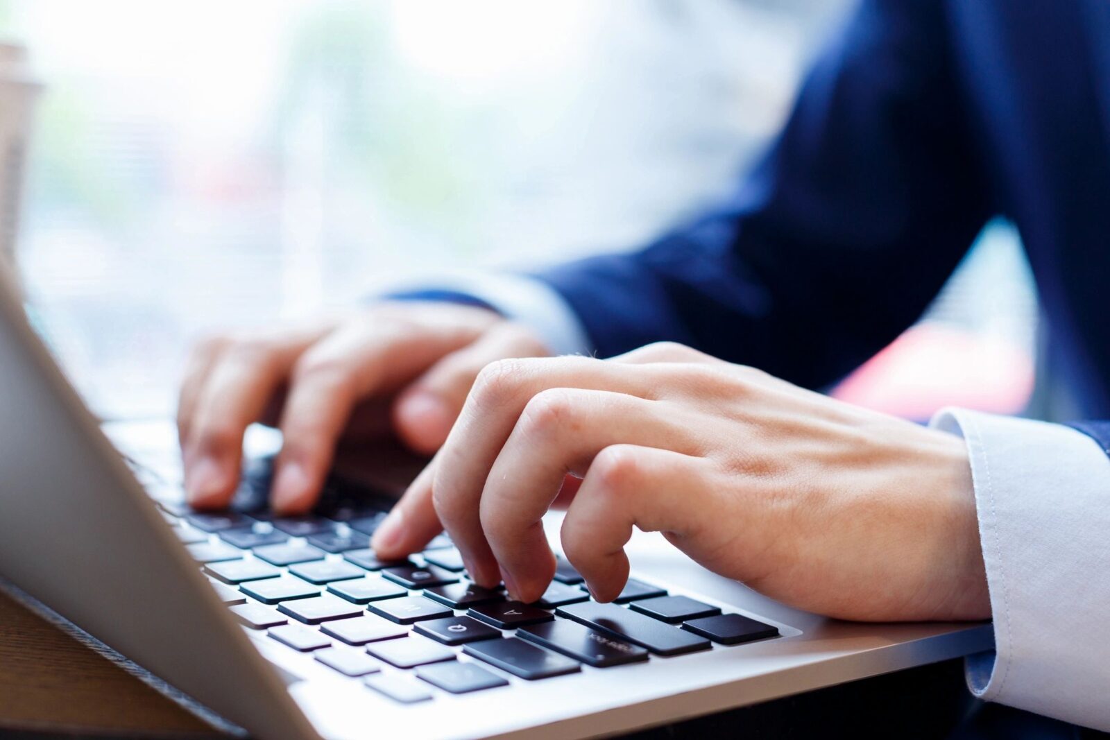 Stock image photo of white hands typing on a laptop keyboard
