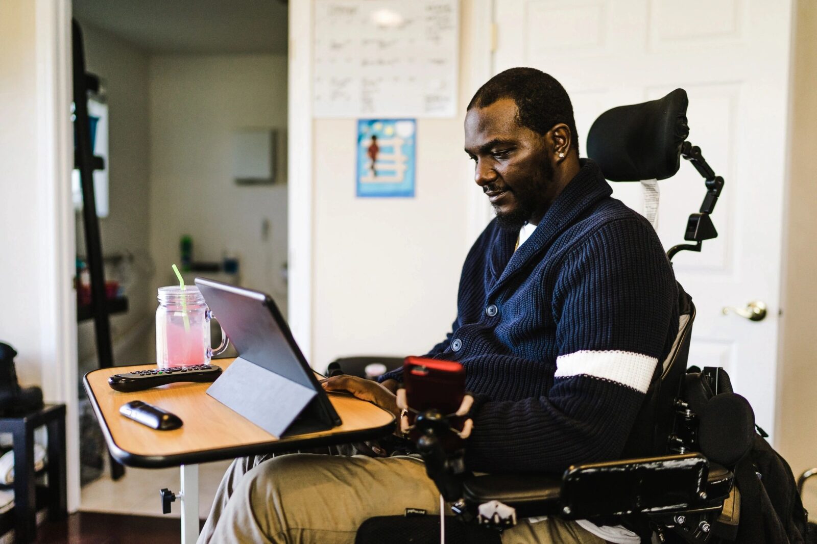 black man in wheelchair communicating through a propped up tablet on a table