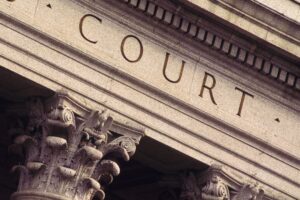 stock photo image of the top of the outside of a building with the word "court" engraved in the marble