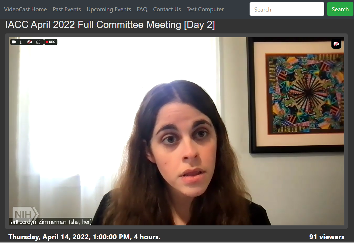Screenshot of Jordyn Zimmerman giving remarks to the NIH IACC with her speech generating device on April 14, 2022. Jordyn is a white woman with long, wavy brown hair, and is wearing a black blazer.
