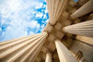 stock photo image of a government building looking up at columns and a blue sky with clouds